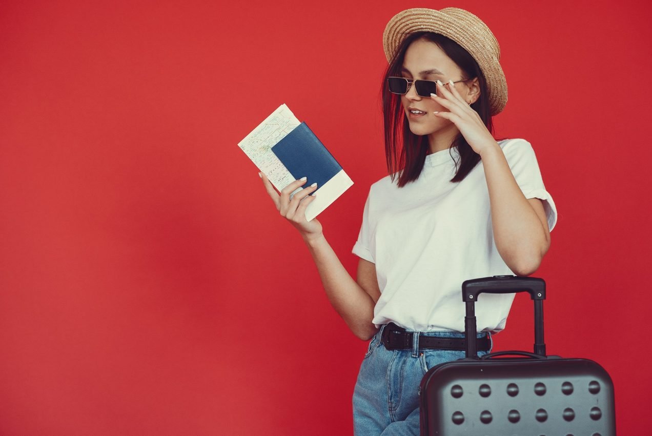 stylish-girl-posing-with-travel-equipment-red-wall1